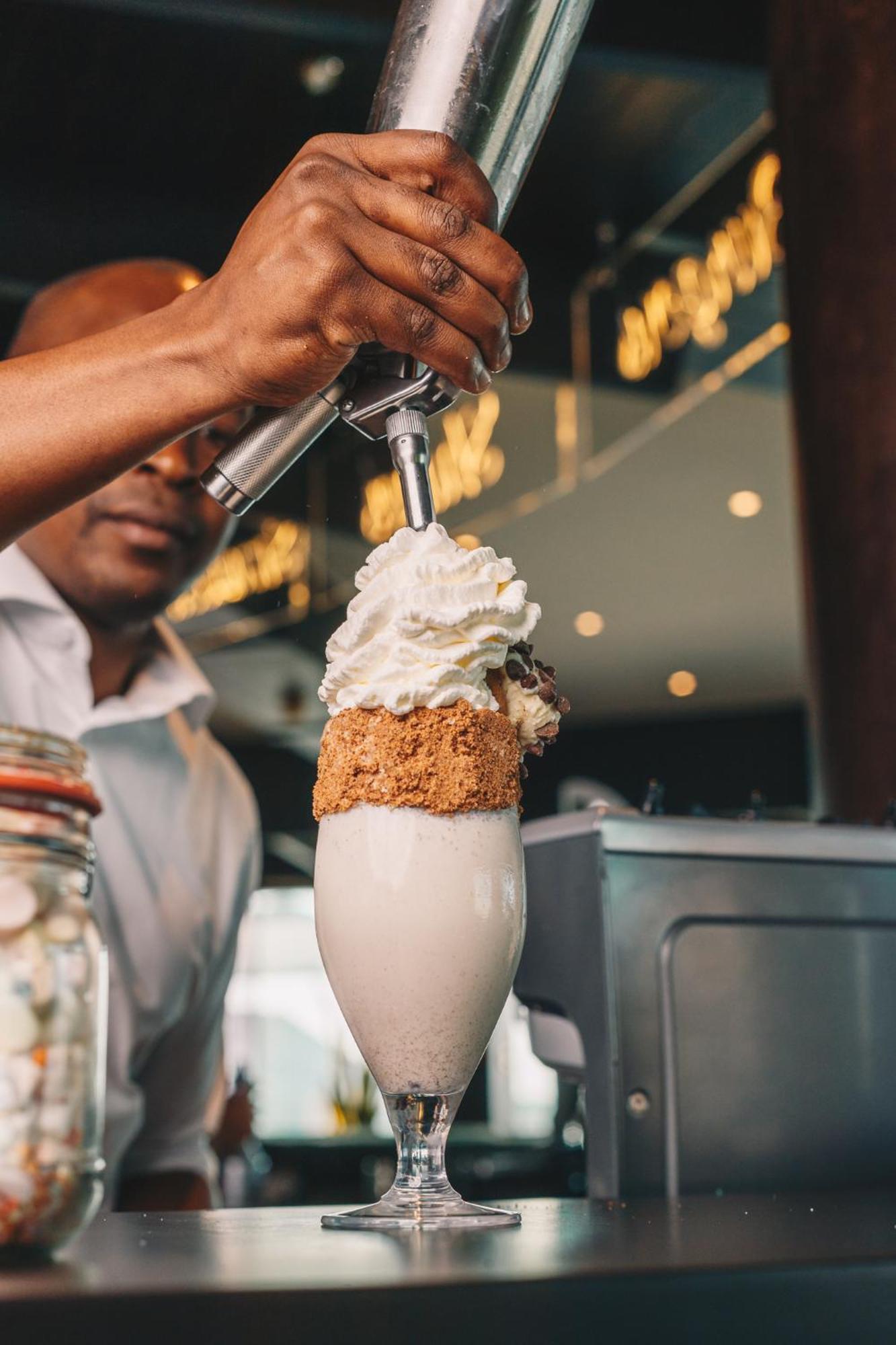 Ja The Resort - Ja Lake View Hotel, Dubai Luaran gambar A barista topping a drink with whipped cream